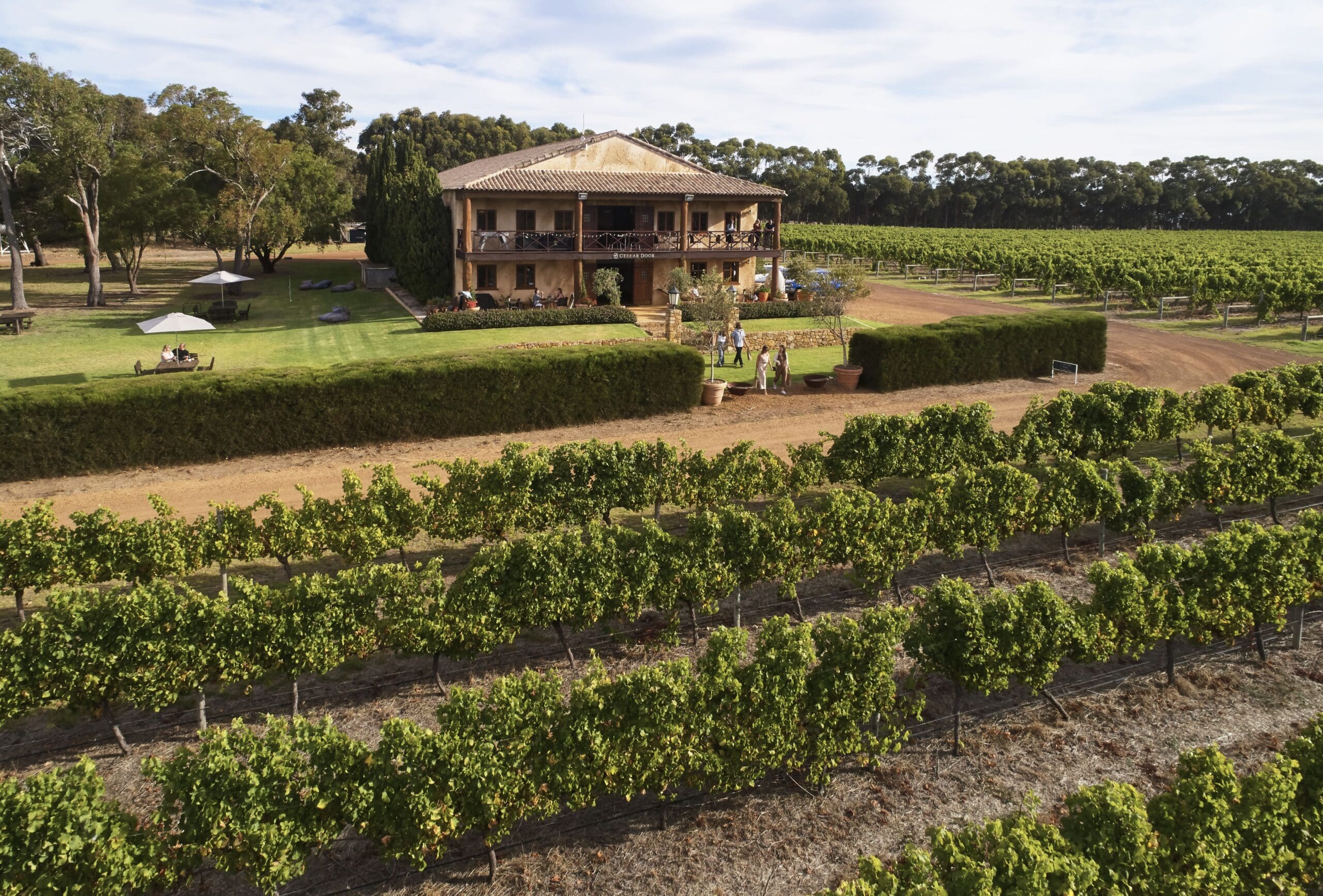 A drone's view of a Tuscan style building surrounded by vineyards