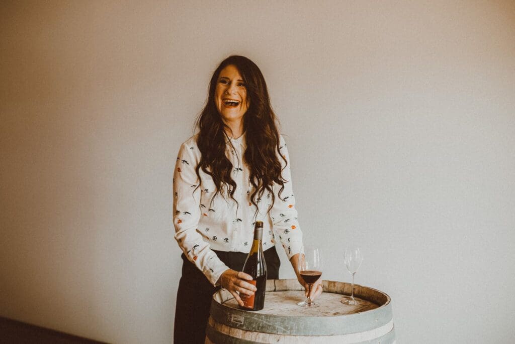 Lady standing next to a wine barrel with glass of wine